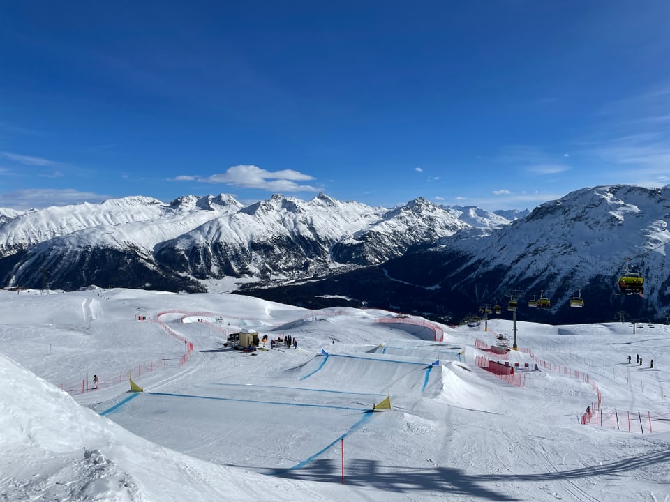 Schneebedeckte Berge mit Skipisten und Sessellift im Vordergrund.