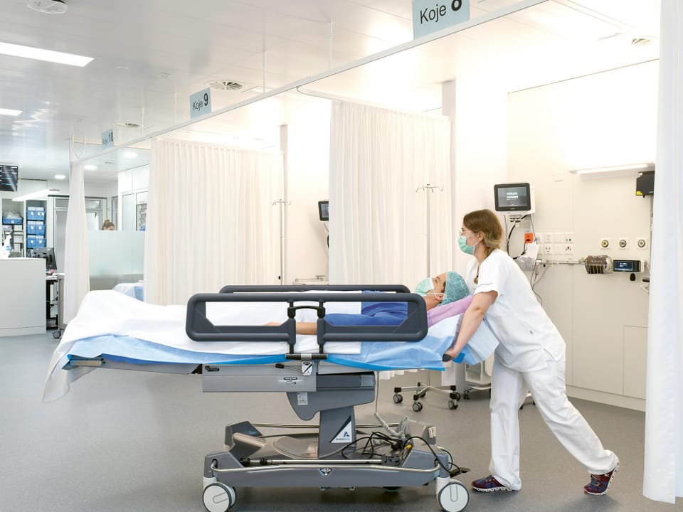 Patientin wird in einem Bett durchs Krankenhaus geschoben. 