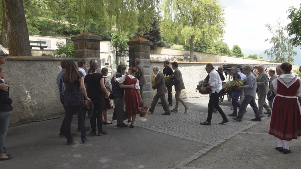 Gruppe von Menschen in traditioneller Kleidung bei einem Umzug im Freien.