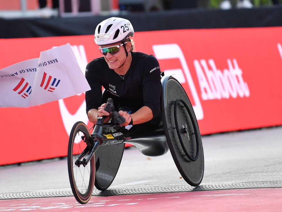 Athlet im Handbike überquert Ziellinie bei Rennen.