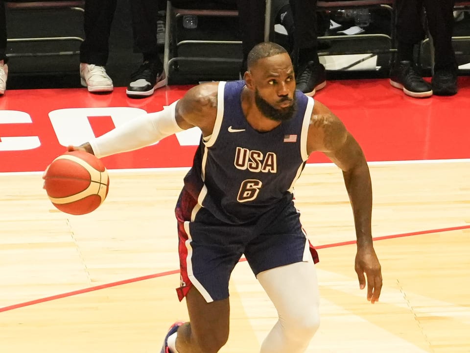 Basketballspieler im USA-Trikot mit Ball auf dem Spielfeld.