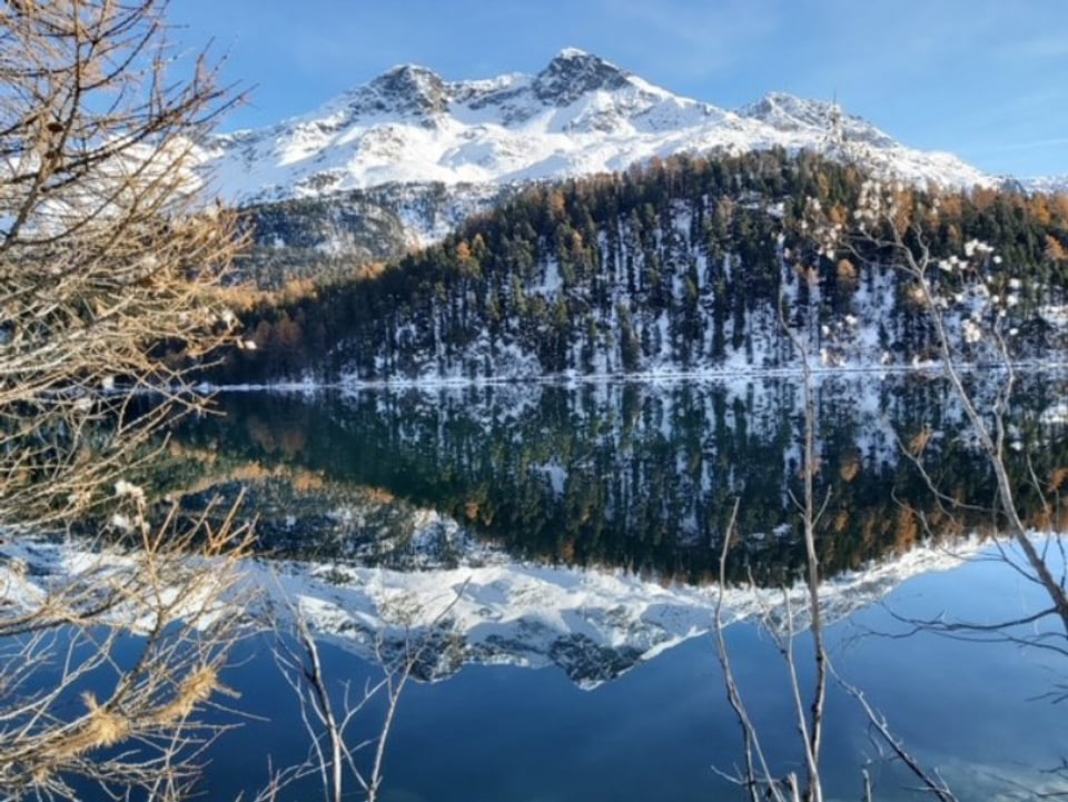 Schneebedeckter Berg spiegelt sich in ruhigem See.