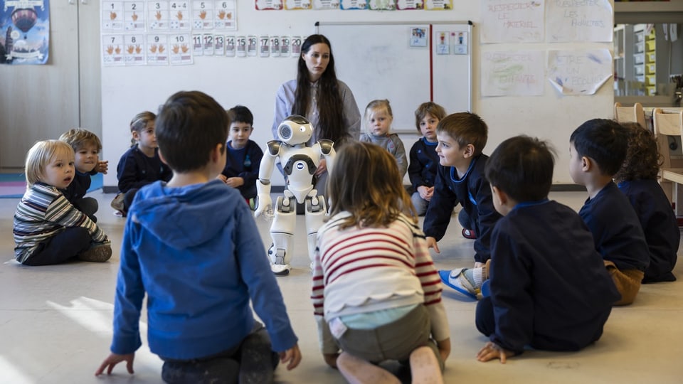 Kinder sitzen um einen Roboter in einem Klassenzimmer.