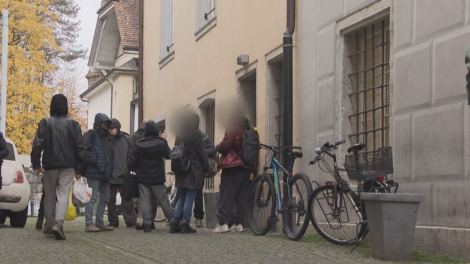 Gruppe von Menschen steht vor einem Gebäude mit Fahrrädern.