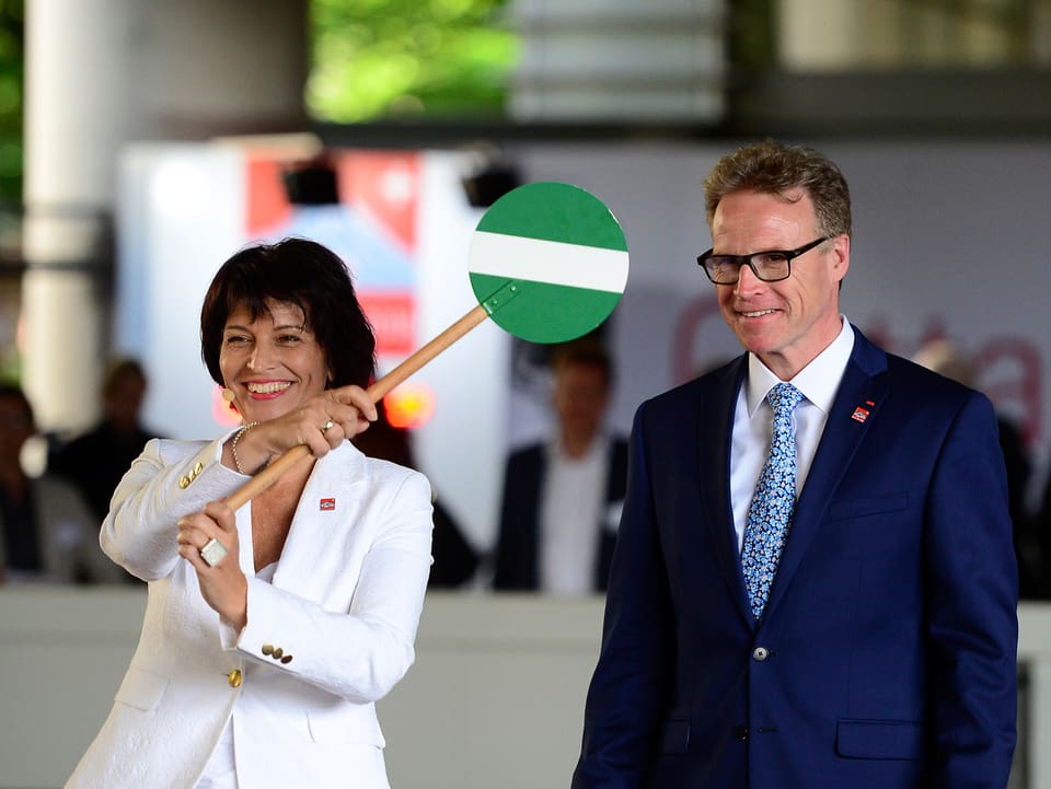 Bundesrätin Leuthard hält ein grünes Strassensignal in der Hand, das die baldige Eröffnung verdeutlichen soll. Neben ihr steht SBB-Chef Meyer.