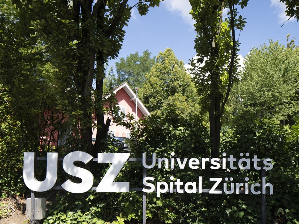 Universitätsspital Zürich-Schild vor grüner Landschaft.