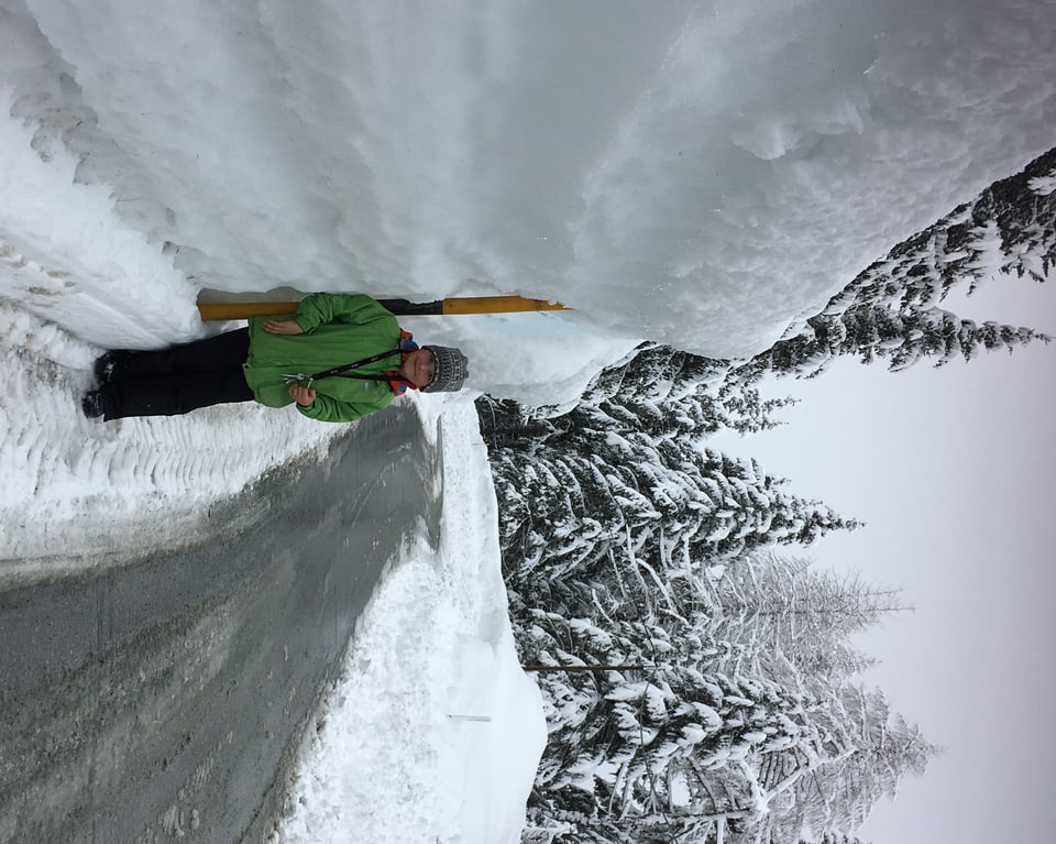 Bub steht auf eienr Strasse neben einer zwei meter hohen Schneewand.