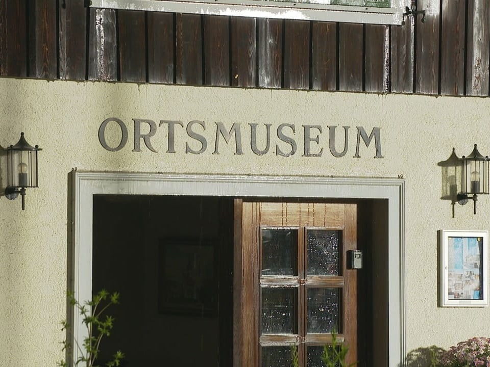 Eingang des Ortsmuseums mit Holztür und seitlichen Laternen.