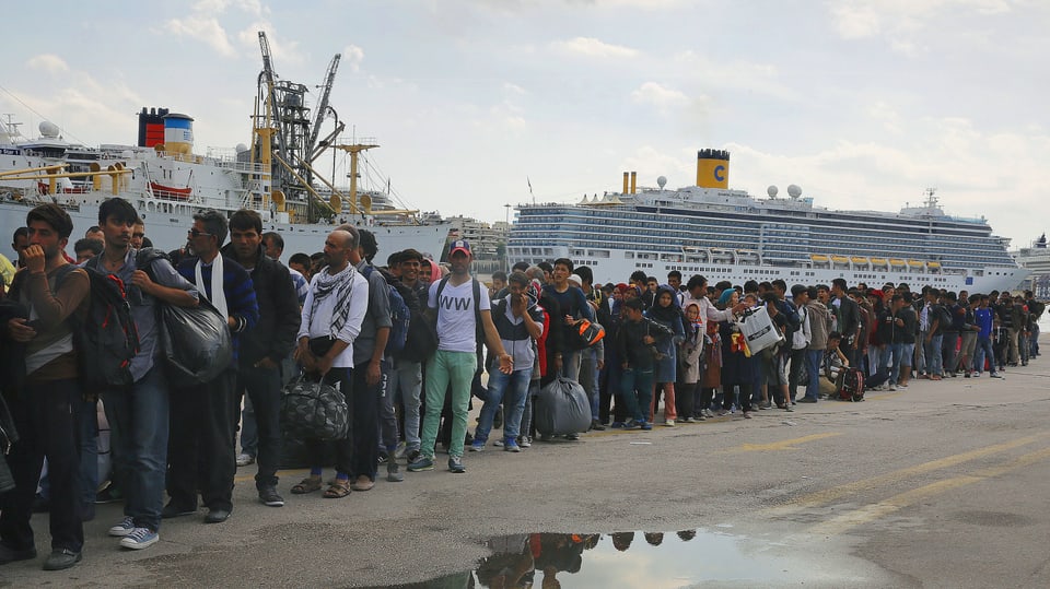 Flüchtlinge warten in einer Schlange.