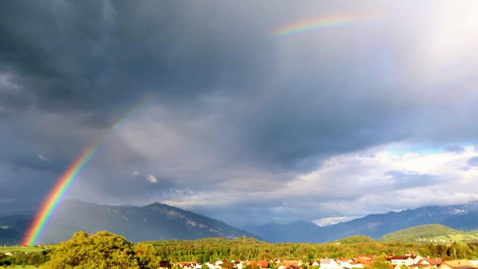 Regenbogen über Landschaft mit Bergen.