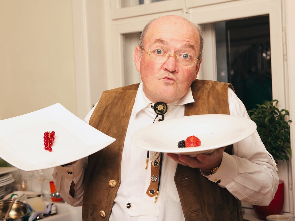 Ein Mann hält zwei Teller in der Hand, auf denen ein paar Beeren liegen.