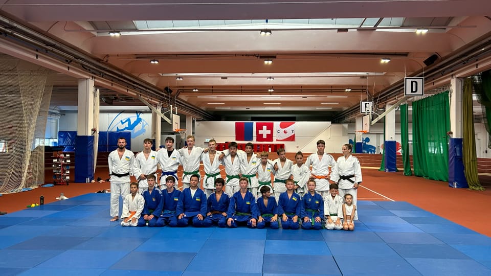 Gruppe von Judoka auf blauem Mattenboden in einer Trainingshalle.