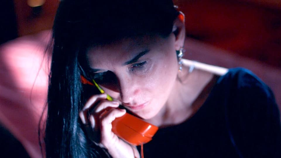 Eine Frau hält sich einen roten Telefonhörer ans Ohr.
