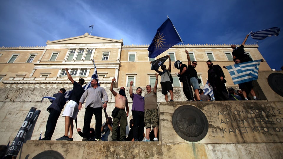 Männer stehen mit Flaggen vor dem griechischen Parlamentsgebäude