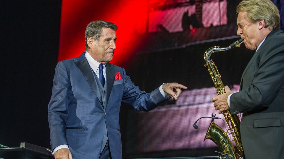 Udo Jürgens auf Bühne zeigt mit Zeigefinger auf saxophonspielenden Pepe Lienhard,