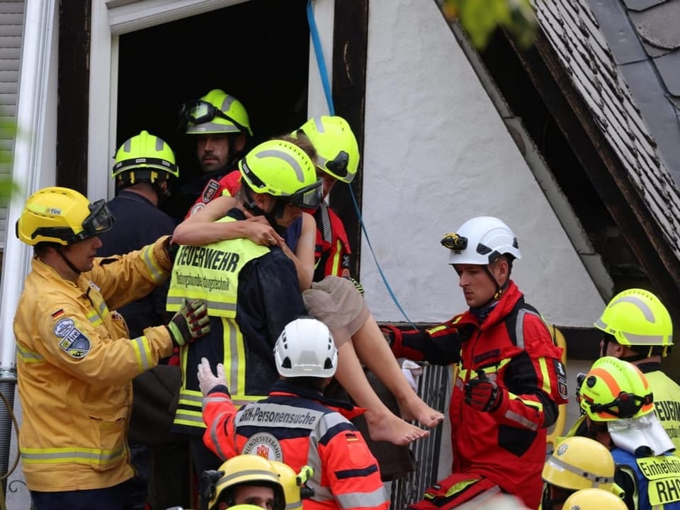 Rettungskräfte retten eine Person durch ein Fenster.