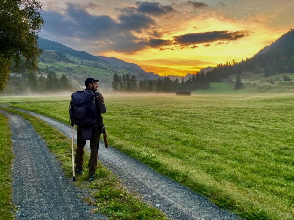 Jäger auf Feldweg bei Sonnenuntergang.