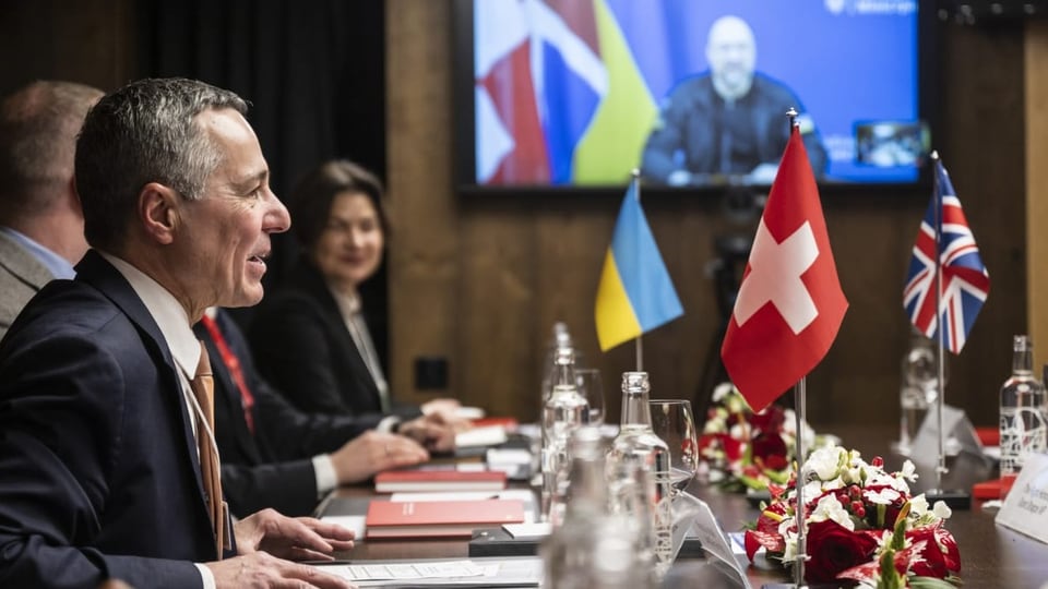 Cassis und weitere Politiker an einem Tisch, Flaggen der Schweiz, Ukraine und Grossbritanniens auf dem Tisch.