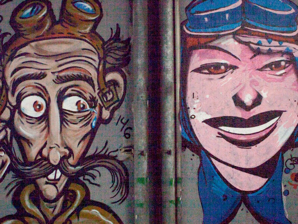 Ein Graffiti eines weiblichen Gesichtes. Das zweite von einem dünnen Mann.