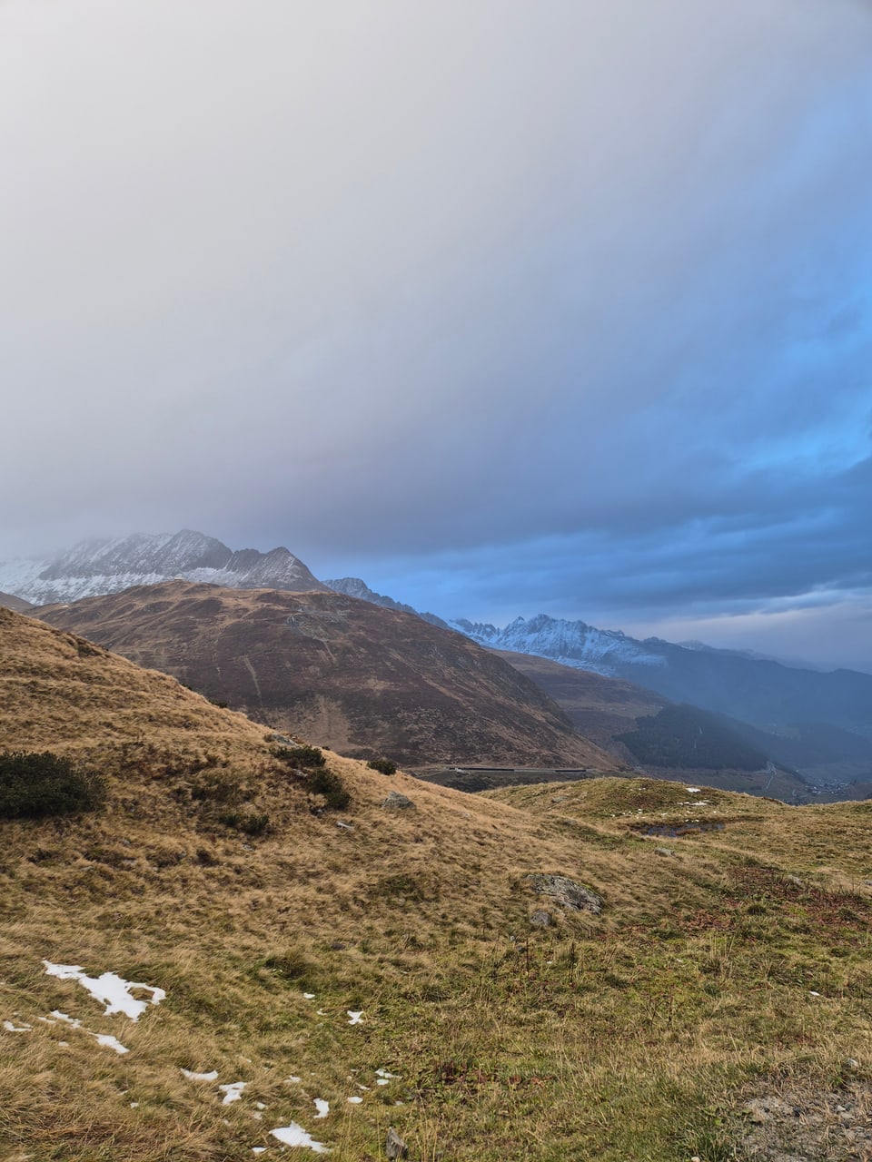 Berglandschaft mit Wolkenhimmel und leichtem Schneefall.