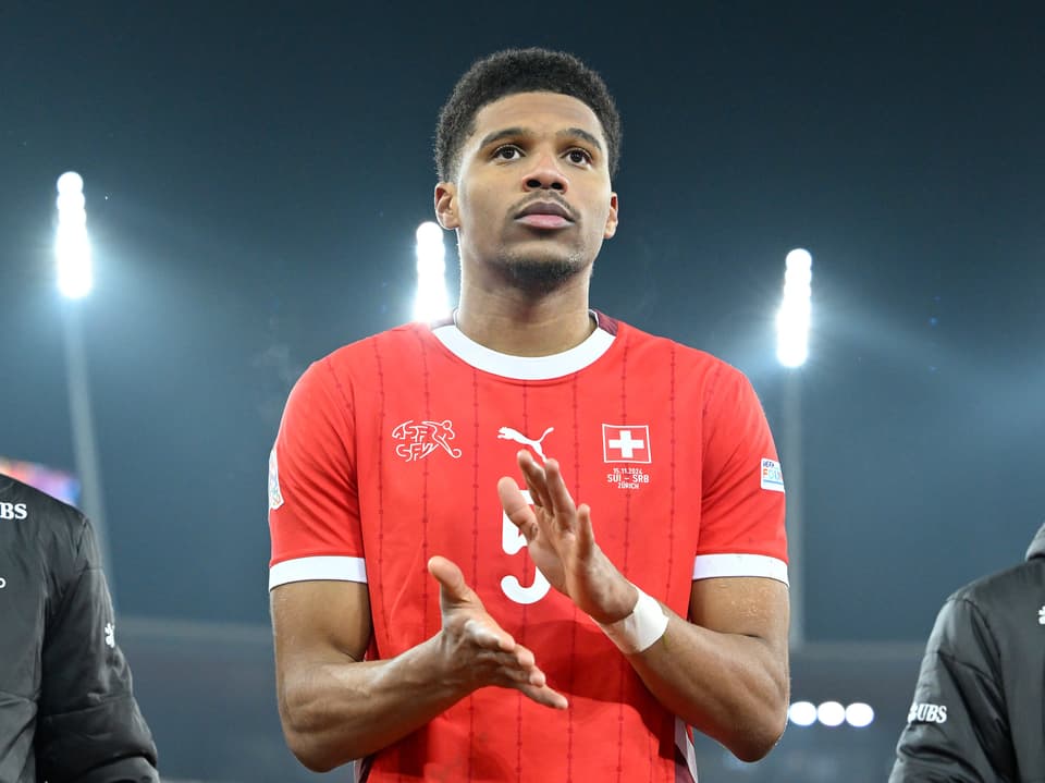 Fussballspieler in rotem Trikot klatscht im Stadion.