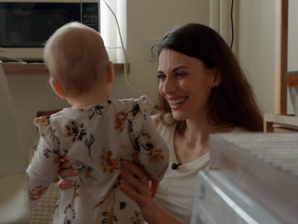 Junge Mutter Wiktorija lächelt ihre 1-Jährige Tochter an.