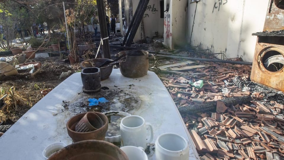 Ein Tisch mit Geschirr vor einem Garten nach der Zerstörung.