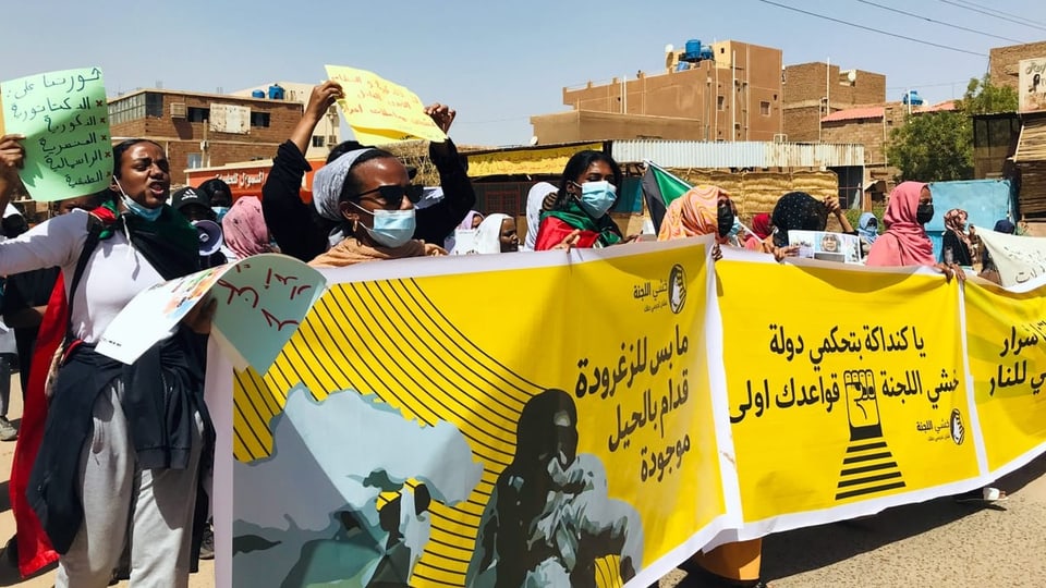 Frauen Frauen demonstrieren auf der Strasse und tragen gelbe Banner vor sich her. 