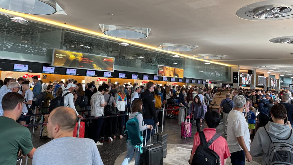 Eine Halle am Flughafen, überall stehen Menschen mit Koffern und Rücksäcken.
