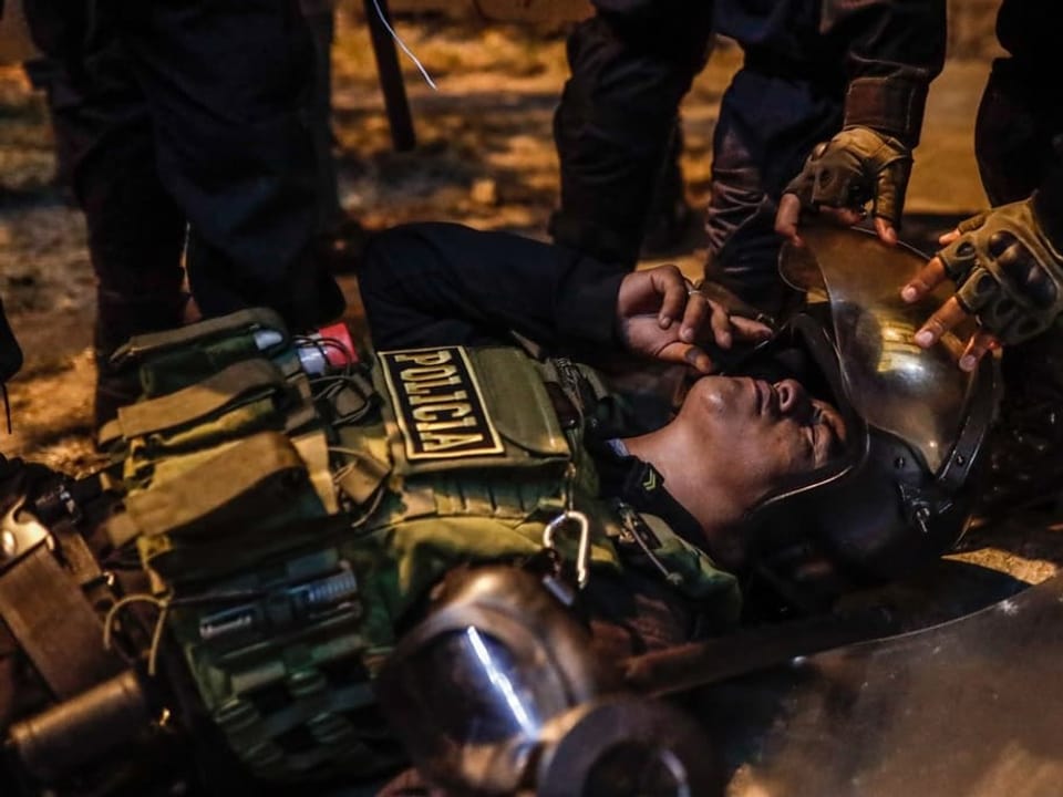 Verletzter Polizeibeamter liegt am Boden und wird betreut.