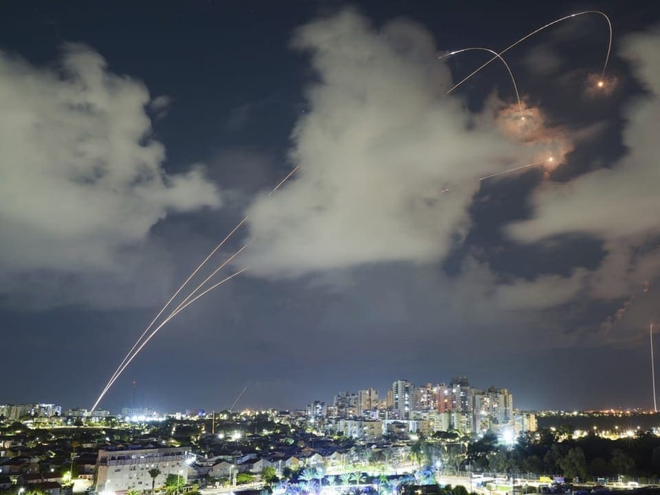Raketen am Nachthimmel oberhalb einer Stadt.