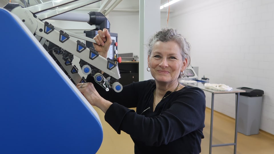 Eine Frau mit grauem Haar bedient eine Maschine.