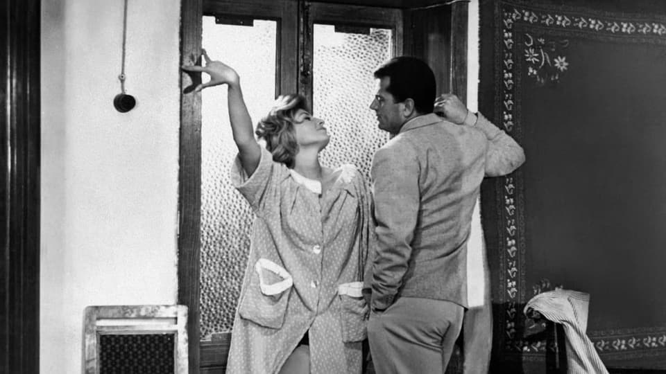 Schwarzweissaufnahme: Eine Frau und ein Mann stehen eng nebeneinander vor einer Tür