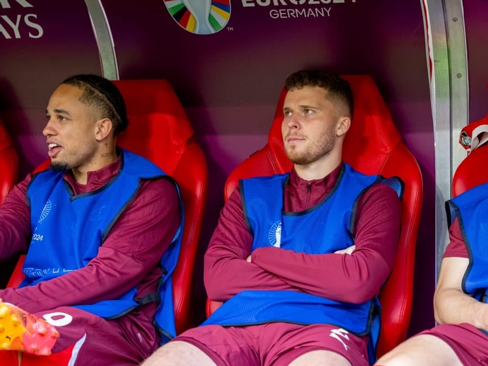Drei Fussballspieler sitzen auf der Auswechselbank während der UEFA EURO 2024.