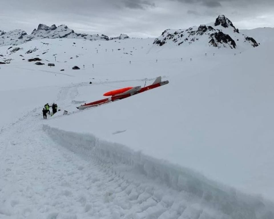 Das Wrack des Jets bei der Absturzstelle. Daneben stehen Personen.