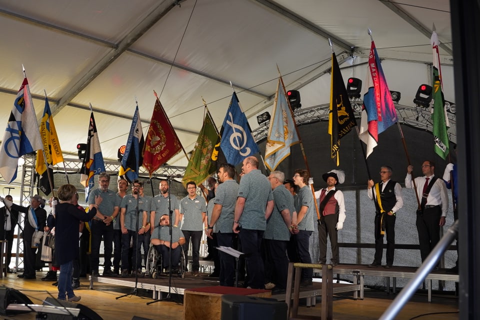 Der Coro Monte Neve Livigno mit allem Fahnenträgern auf der Bühne im Festzelt.