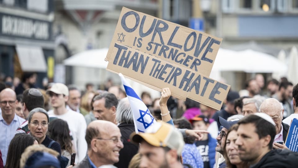 Eine Person hält ein Schild in die Höhe. Darauf geschrieben: «Our Love is stronger than their hate».