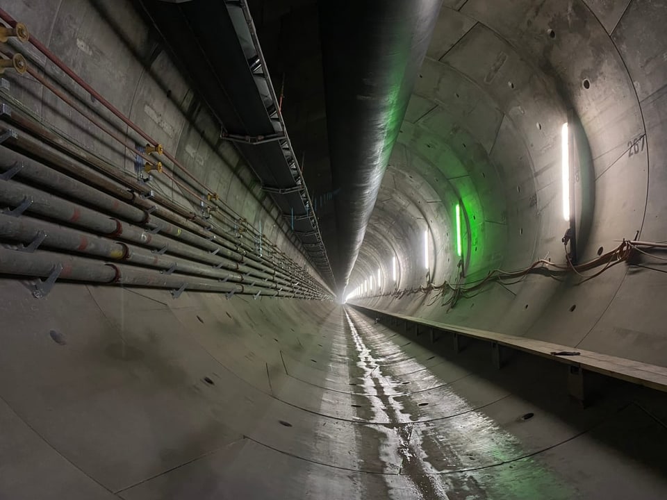 Grosser beleuchteter Tunnel mit Kabeln an den Wänden.