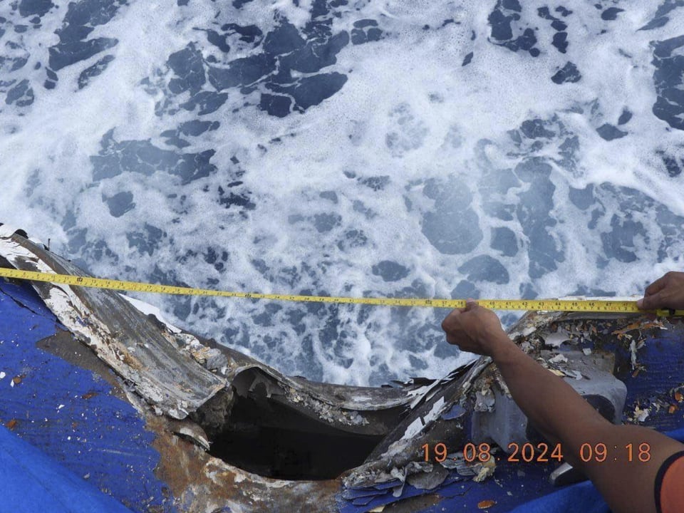 Person misst ein beschädigtes Boot über wellenartigem Wasser.