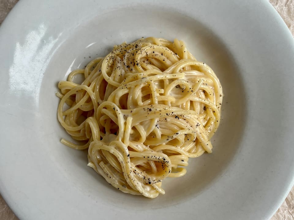 Teller mit Spaghetti in Käsesauce und Pfeffer.