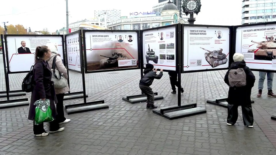 Menschen betrachten Ausstellungstafeln im Freien.