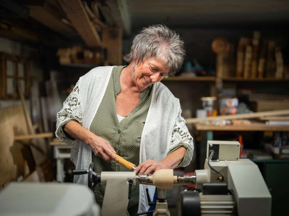 Frau arbeitet in Werkstatt an einer Drehbank.