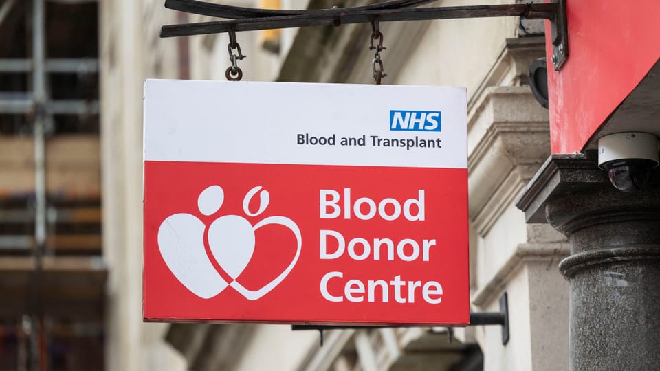 Schild des Blutspendezentrums mit NHS-Logo.