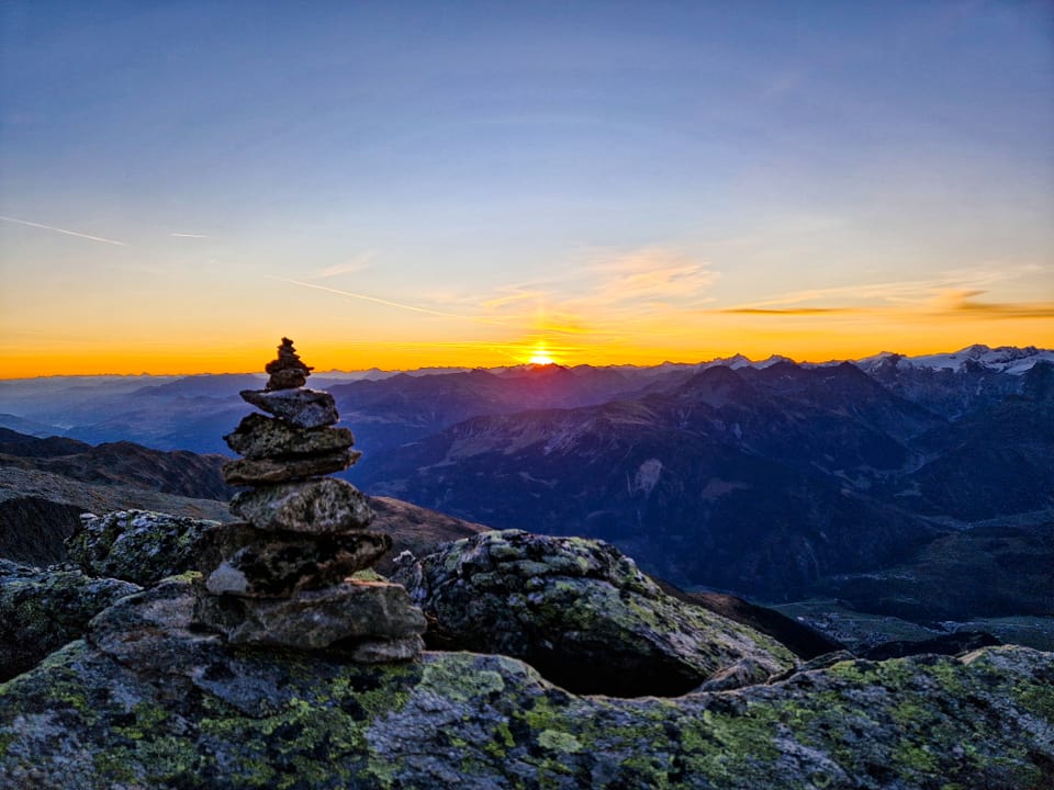 Steinhaufen auf Berggipfel bei Sonnenuntergang.