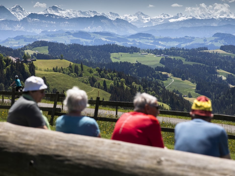 Vier Senioren sitzen vor einer Berglandschaft.