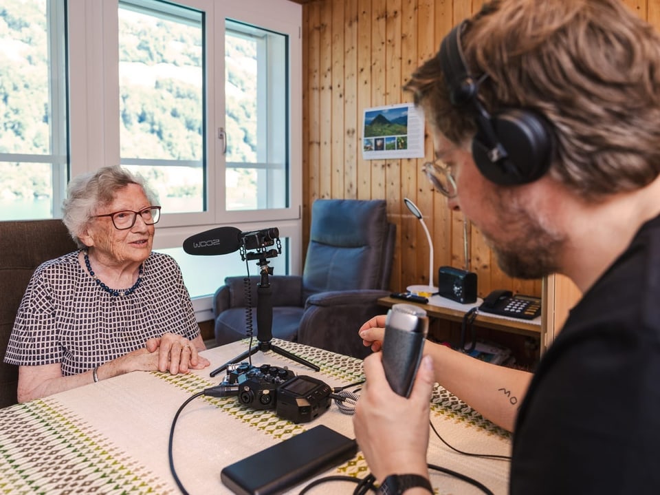 Marie Vogler-Gasser und Michael Zezzi sitzen an einem Tisch, auf welchem Mikrofone aufgestellt sind.