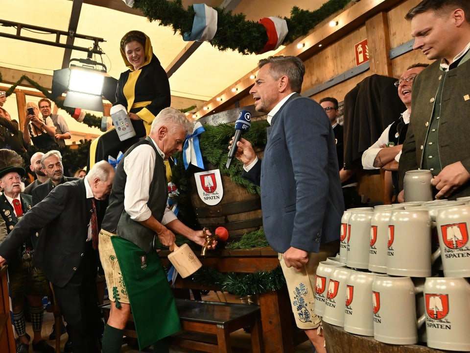 Szenen aus einem Oktoberfest-Zelt mit einem Mann, der ein Bierfass anzapft.