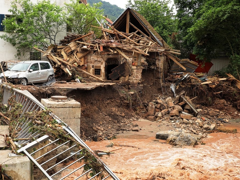 Überschwemmungsschäden an einem zerstörten Haus mit Schlammstrom.