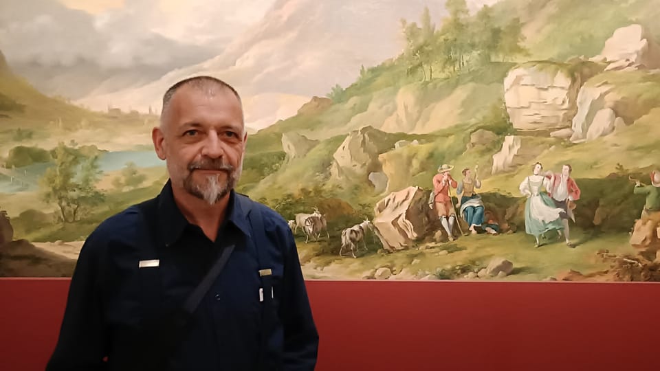 Mann im Museum vor einem Gemälde mit Landschaftsszene.