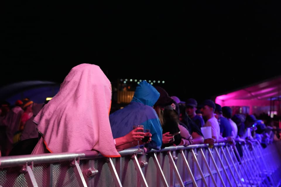 Menschen bei einem Konzert im Regen unter einer Abdeckung.